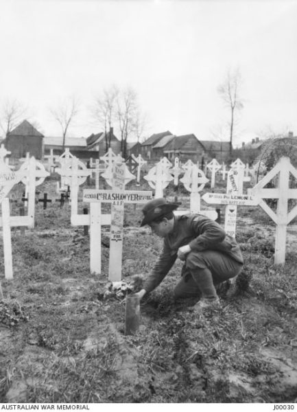 A soldier lays flowers on the grave of a friend, France 1919