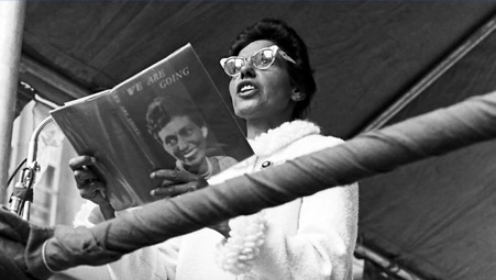 Photograph of Oodgeroo Noonuccal, then known as Kath Walker, reading from her own poerty collection at the National Aborigines Day celebration in Martin Place, Sydney, 9 July 1965.