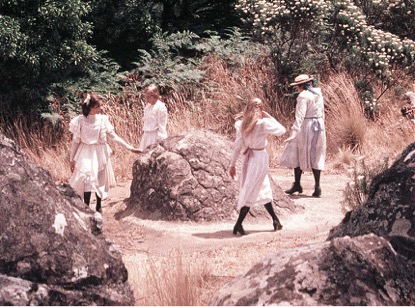 Image of the Film “Picnic at Hanging Rock” with 4 girls walking around the rock.