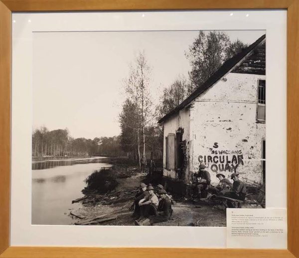 Australian Soldiers resting at the ferry landing on the bank of the River Somme. Painted on a building behind the soldiers is a reference to Circular Quay a famous large ferry terminal in Sydney, Australia.