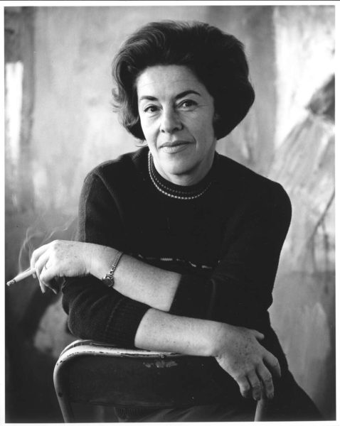 A black and white portrait of Judy Cassab with a cigarette in her hand.