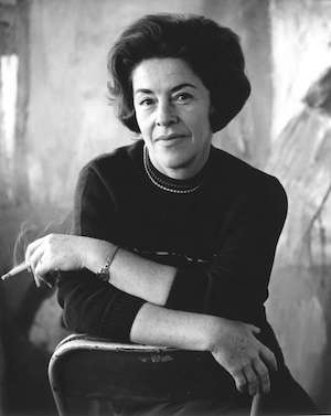 A black and white portrait of Judy Cassab with a cigarette in her hand.