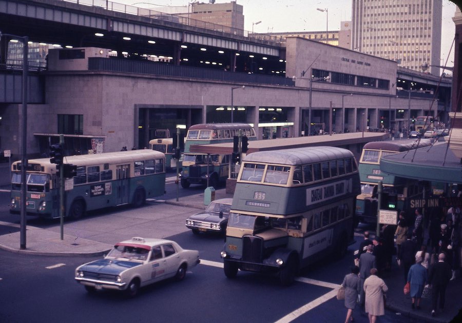 Photograph of Circular Quay Station. Parked outside are green double-decker buses.