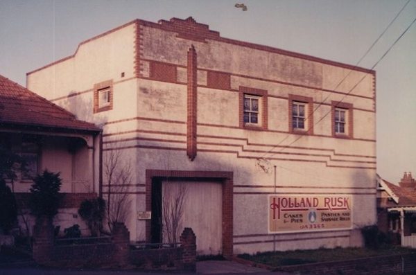 A photograph of an art deco building with the sign 'Holland Rusk Cakes & Pies'