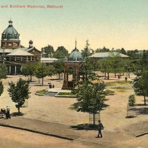 Postcard showing the Soldiers Memorial at Bathurst. The memorial is situated in the centre of a park lined with trees. A public building is visible in the background.