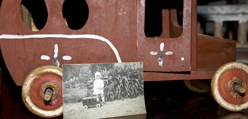 A wooden toy bus and a photograph of a small boy with the toy bus.