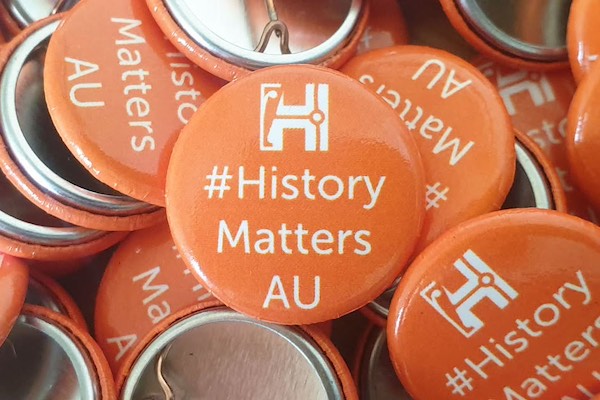 A collection of orange-coloured buttons, featuring the text: #History Matters AU