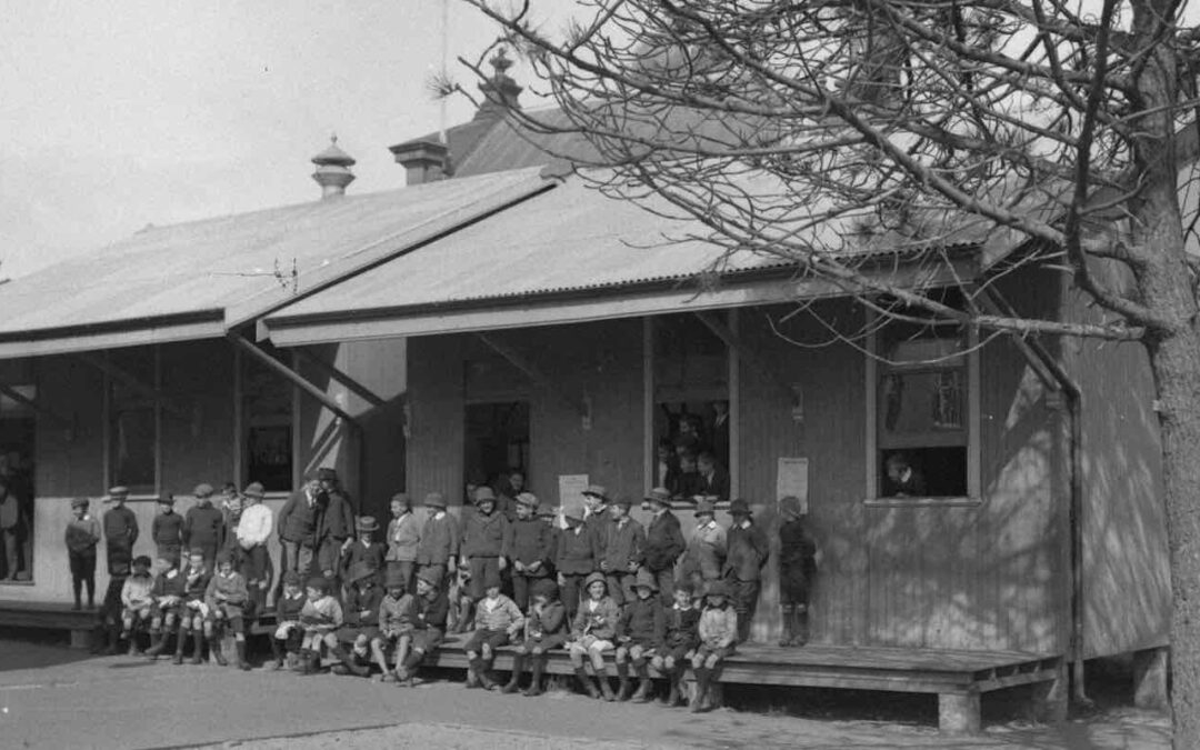 A portable classroom with students and teachers sitting on the verandah
