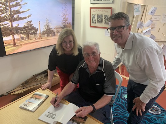 Photograph of Debbie Sommers, Tony Dawson, and Robert Dwyer MP. Tony Dawson signs a copy of the book, 'Clarence Street, Port Macquarie'.